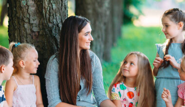 Frau liest Kindern im Park vor