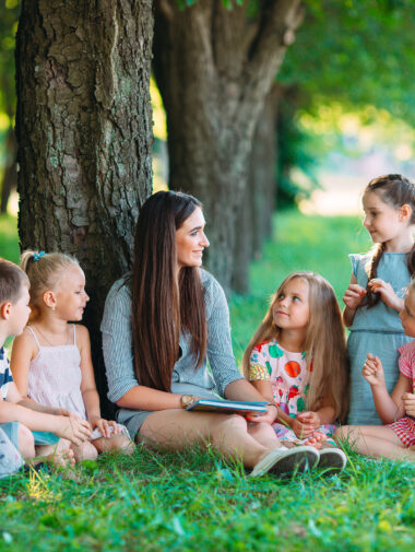 Frau liest Kindern im Park vor